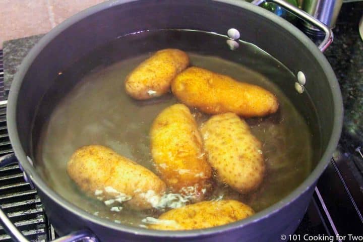 six potatoes boiling in black pan