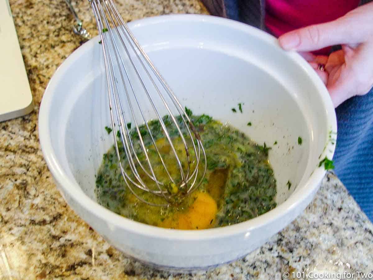 whisking herbs with eggs and milk.