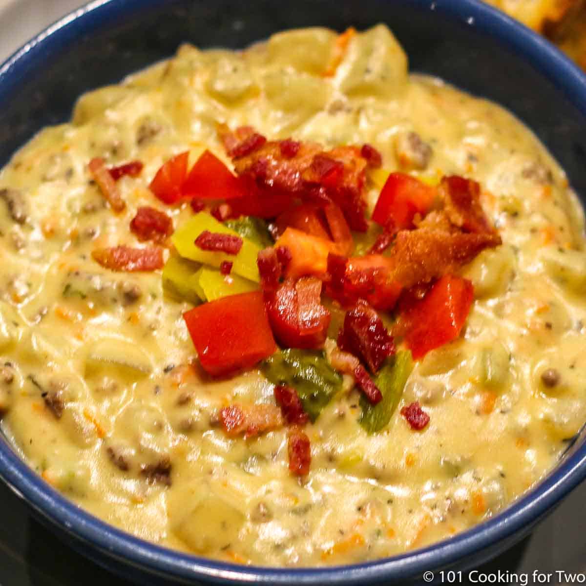 cheeseburger soup in a blue bowl with toppings