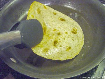 crisping a tortilla in oil in black pan