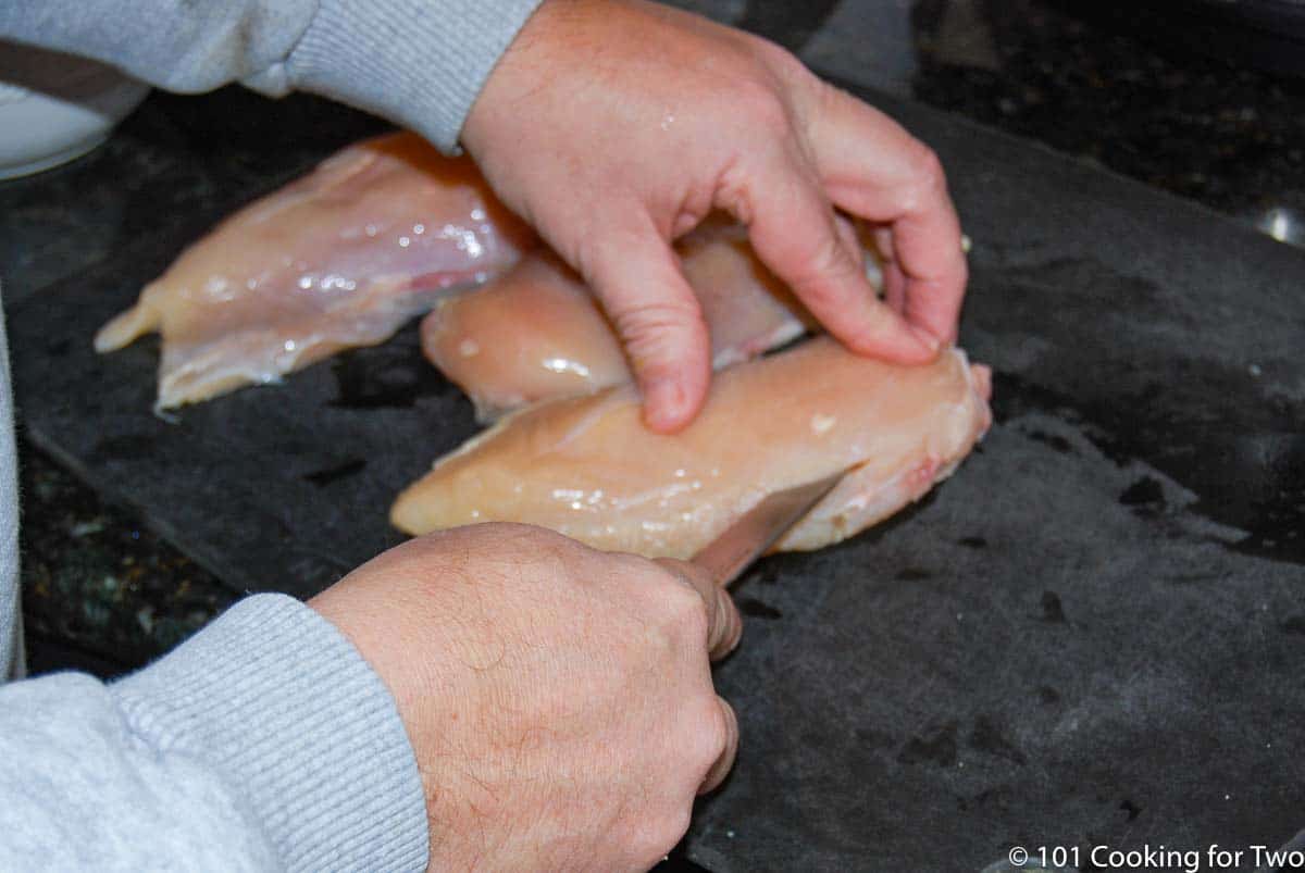 cutting slit into chicken breast for stuffing.