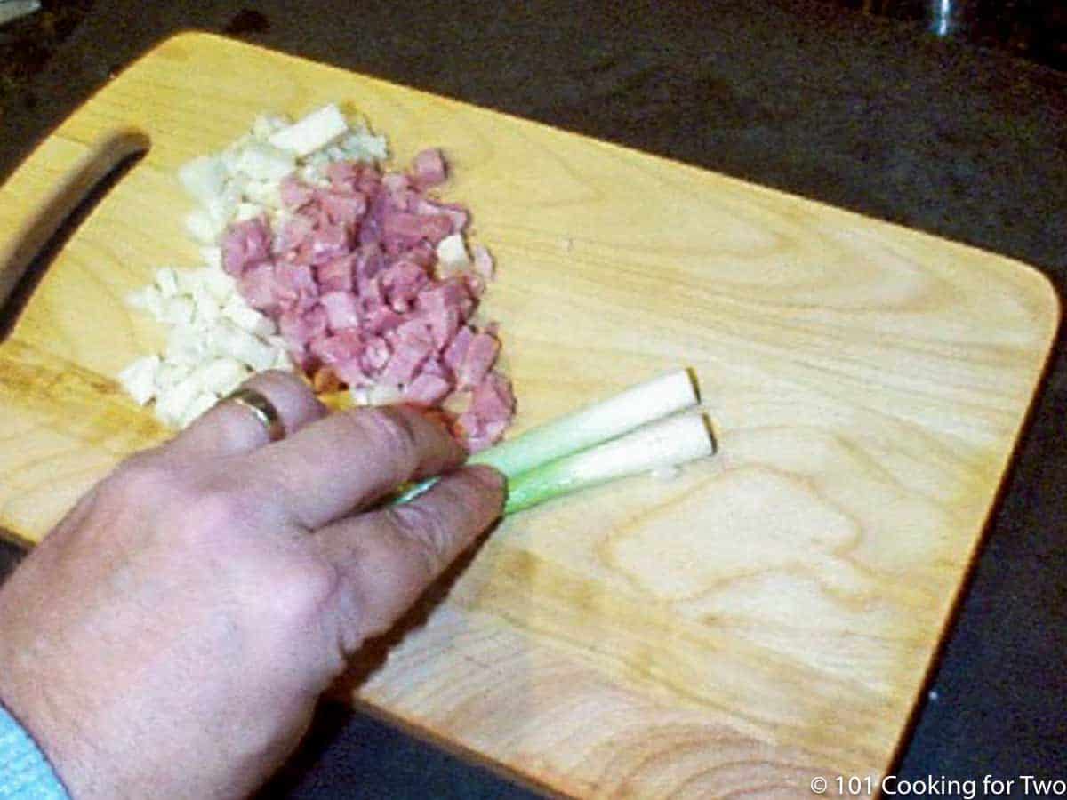 cutting up onion with ham and cheese on board
