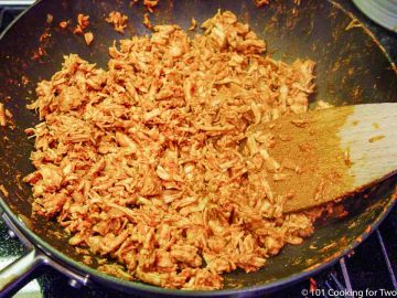 mixing shredded chicken with sauce