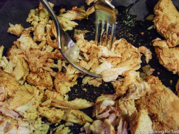 shredding cooked chicken on black board