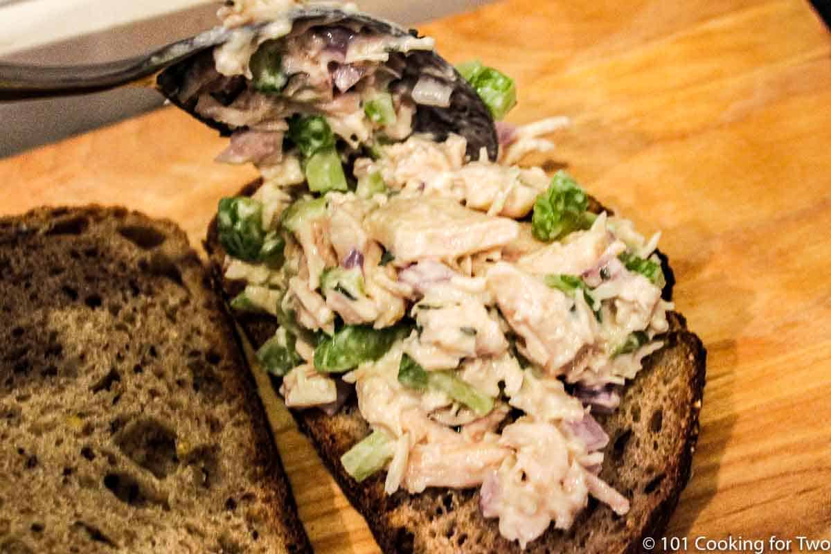 spooning chicken salad onto bread