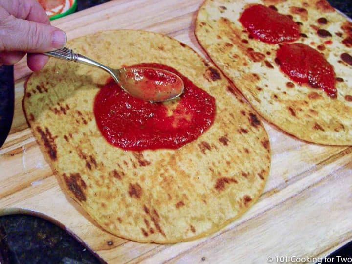 spreading sauce on browned flat bread