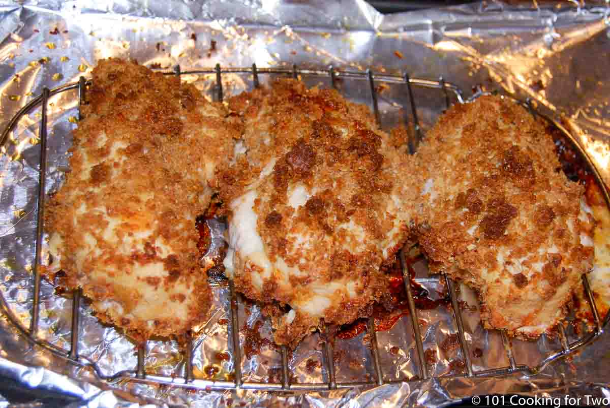 three cooked chicken breaats on tray.