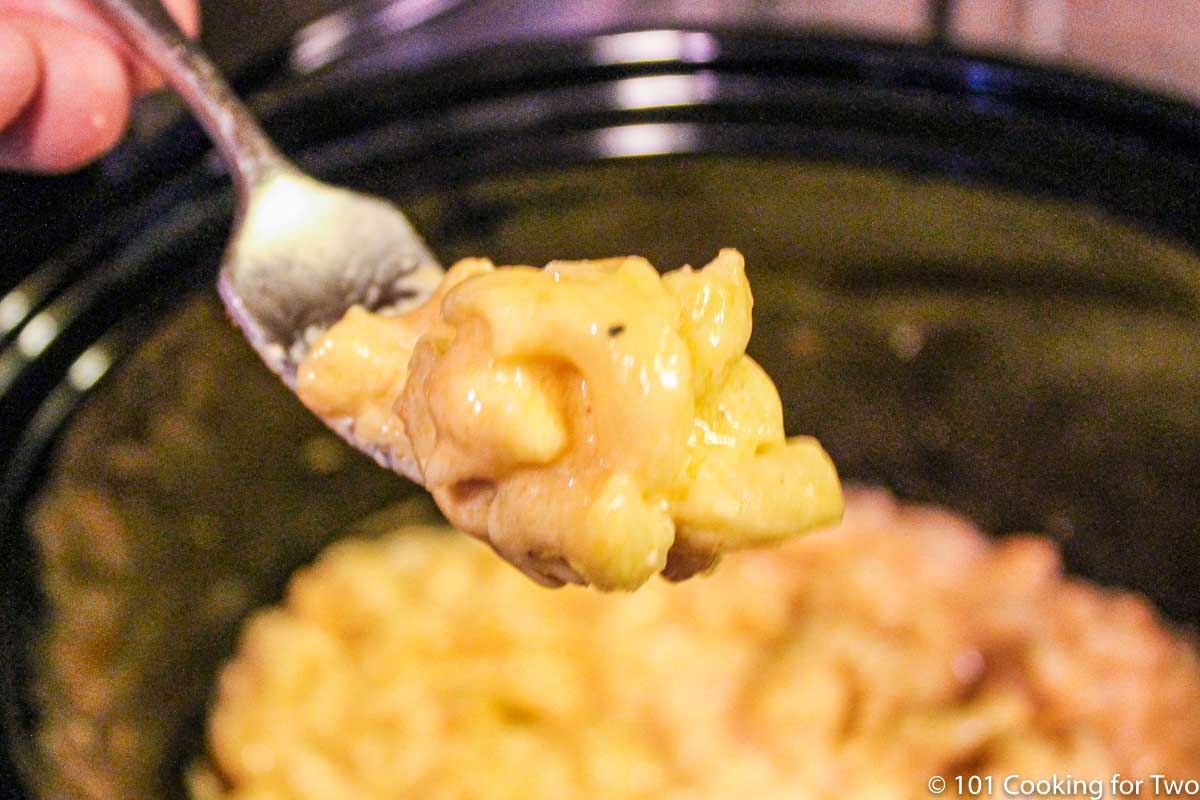Mac and cheese on fork over crock pot.