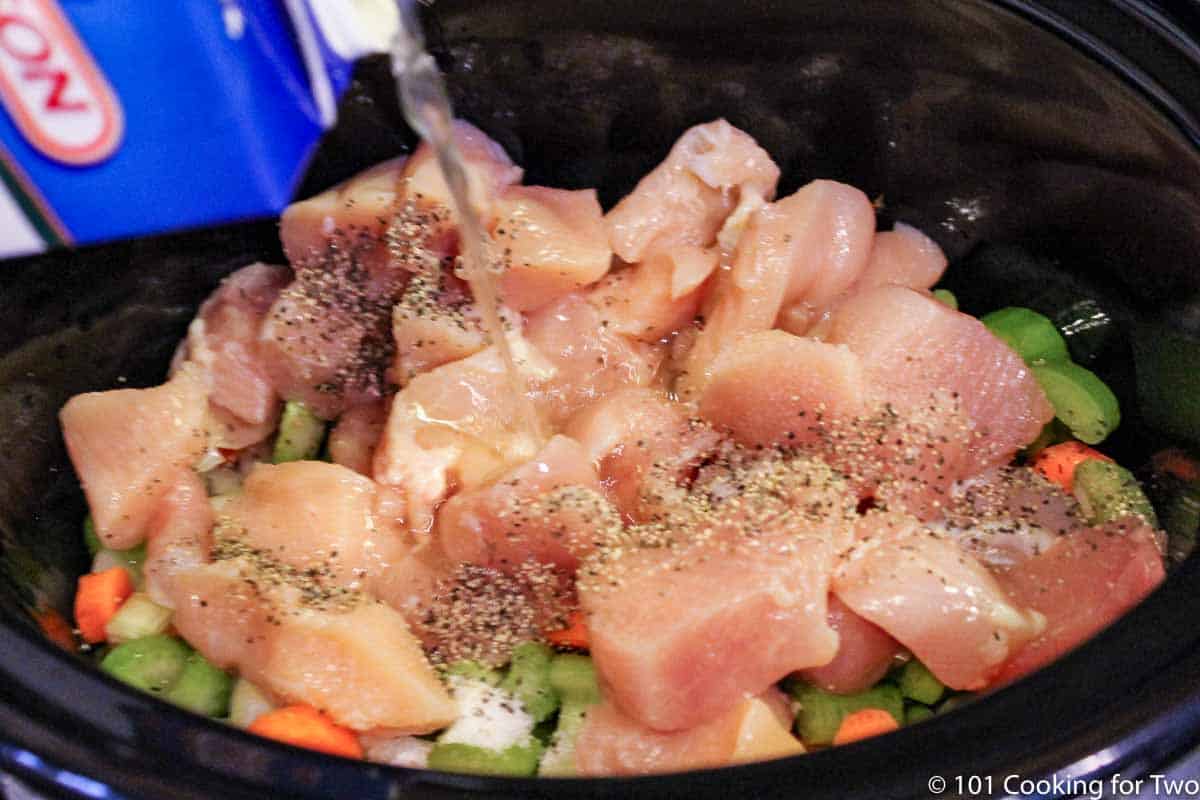 adding broth to all other ingredients in the crock pot.