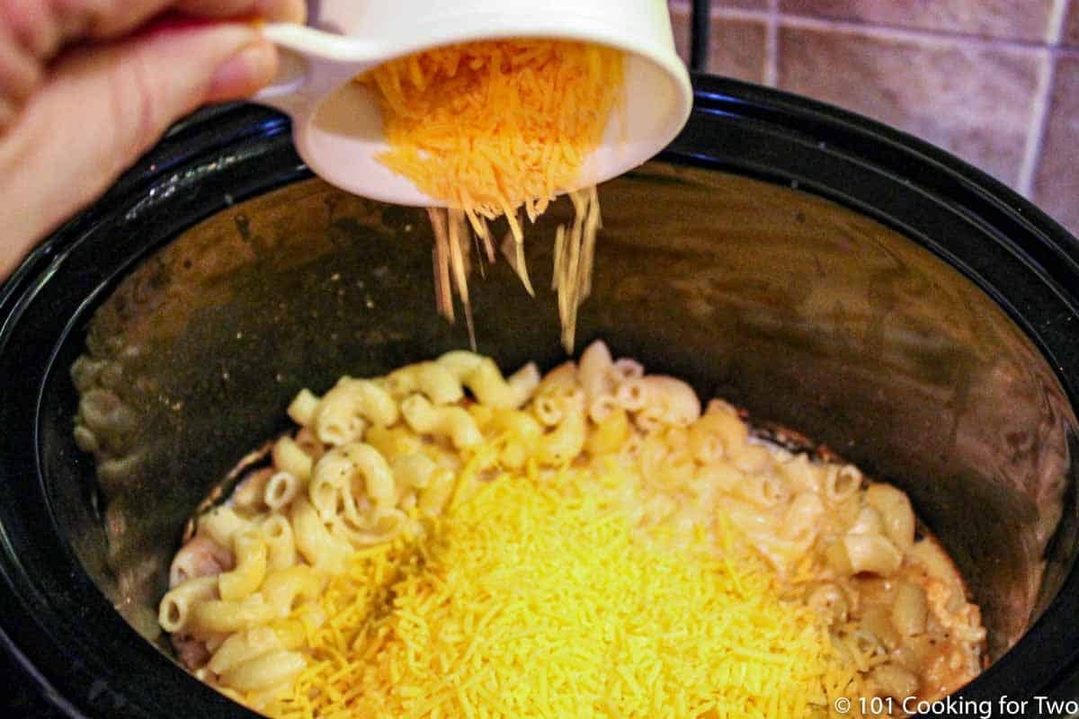 adding cheese to cooked macaroni.