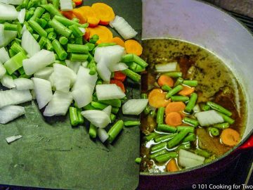 adding chopped vegetables to the pot