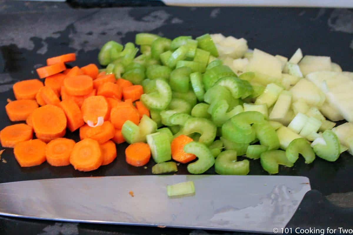 chopped carrots with celery and onion on a black board.