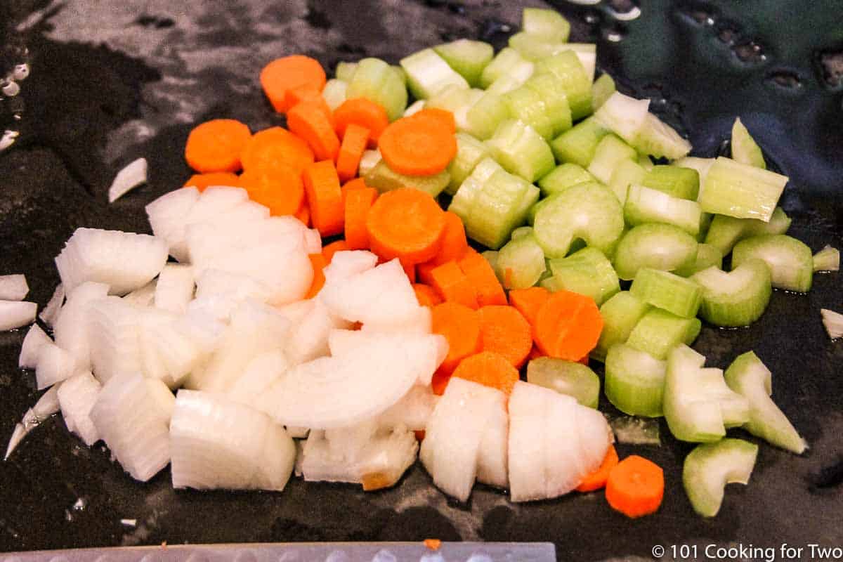chopped onion with carrots and celery on a black board.