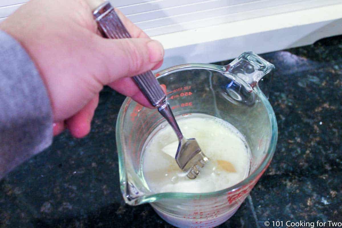 mixing milk with egg in a measuring cup.