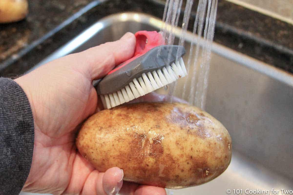 scrubing a potato under running water.