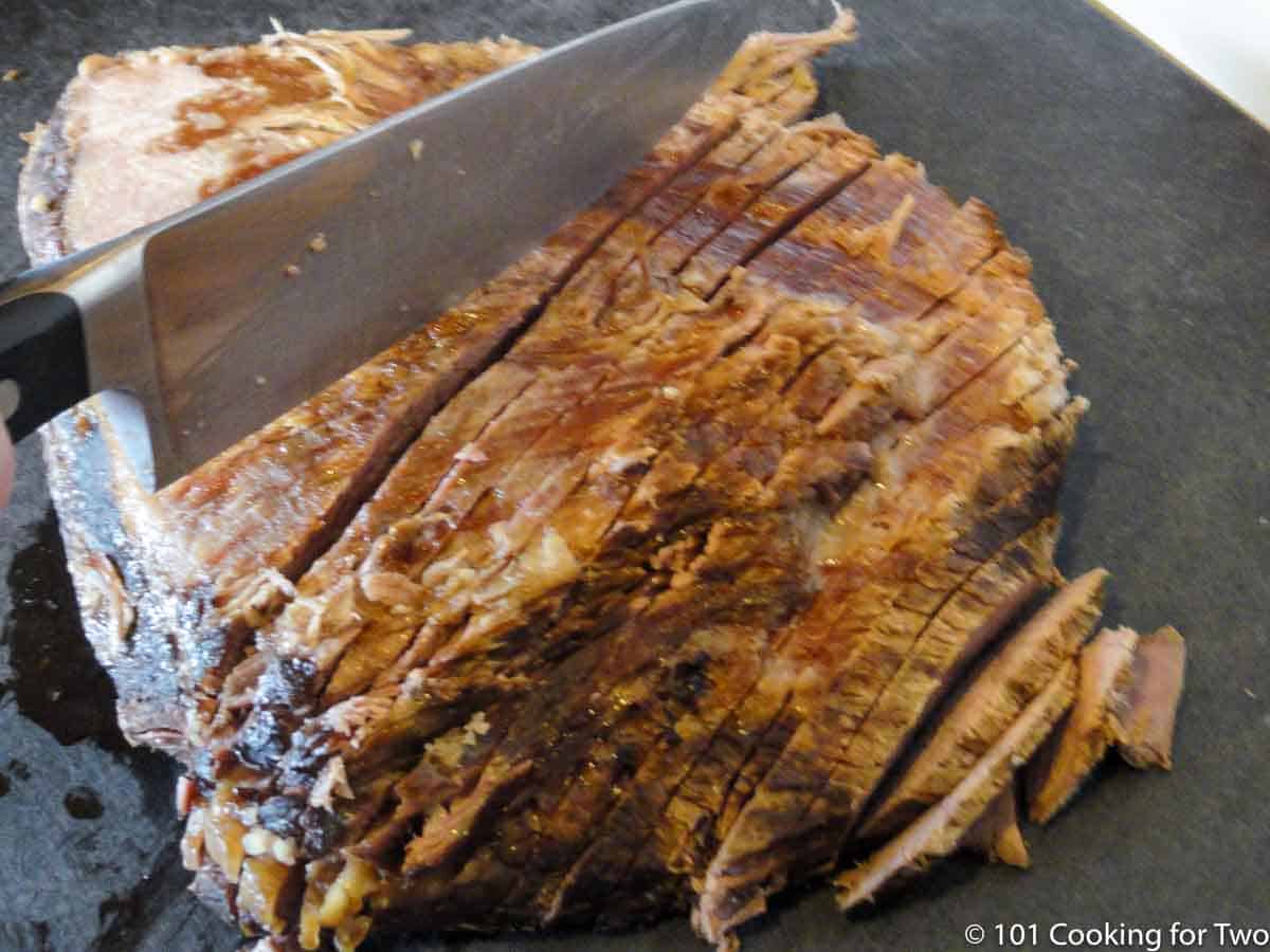 slicing the cooked brisket cross-grain.