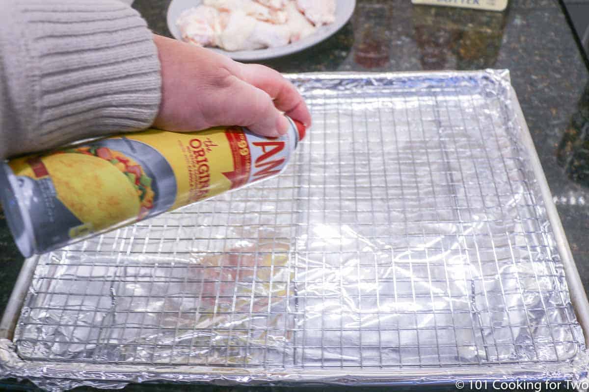 spraying a baking rack with PAM on a baking tray.