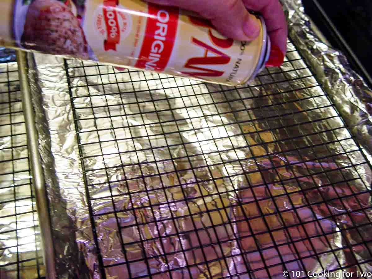 spraying rack on foil covered tray with PAM