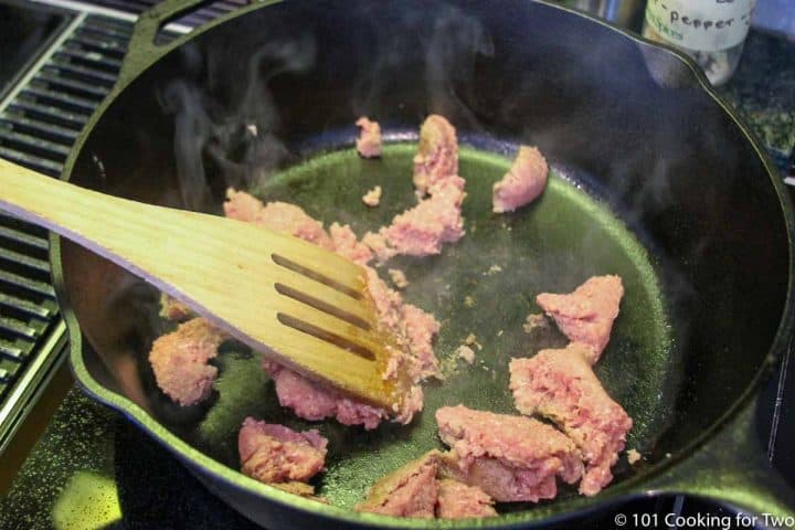 breaking up sausage in a large skillet