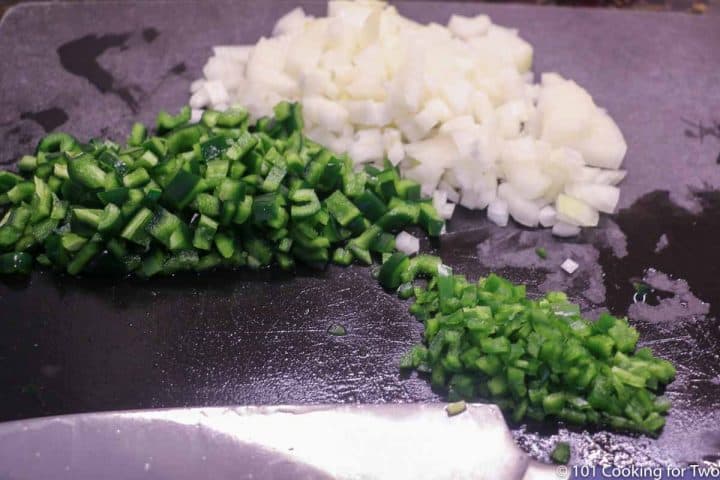 chopped onions and peppers on a black board