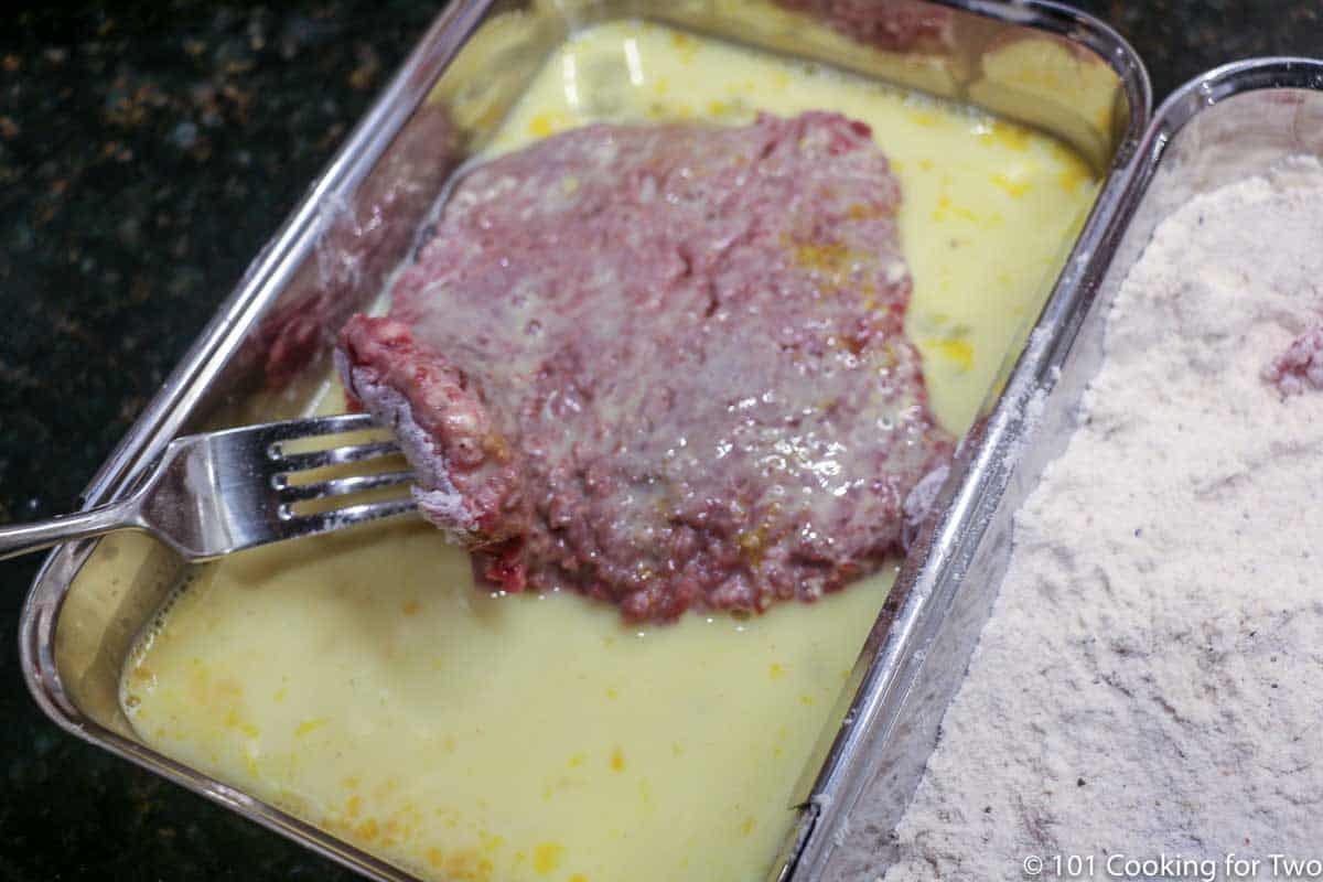 coating the meat with egg mixture.