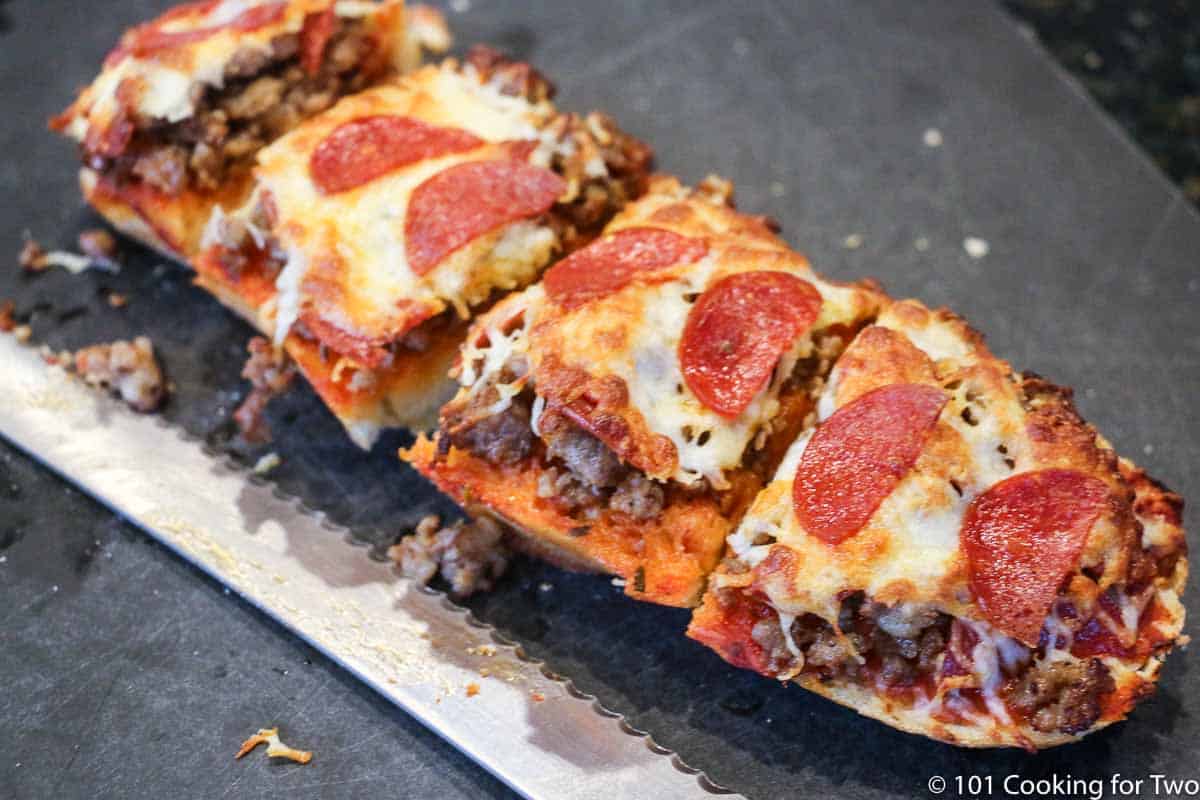cut up French bread pizza on black board.