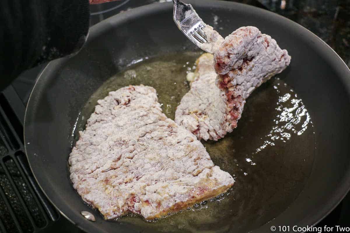 laying the coated meat into the hot oil.