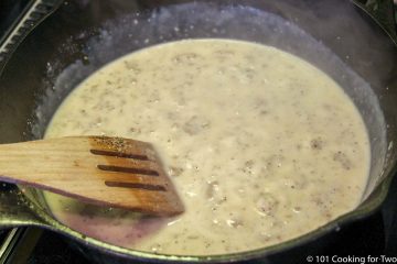 stirring sausage gravy in skillet