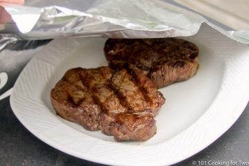 tenting two filets with foil on a white plate