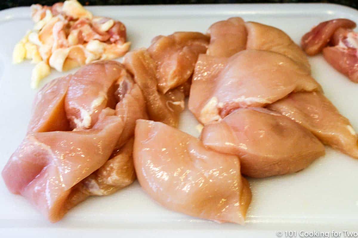 trimmed raw chicken on a white board.