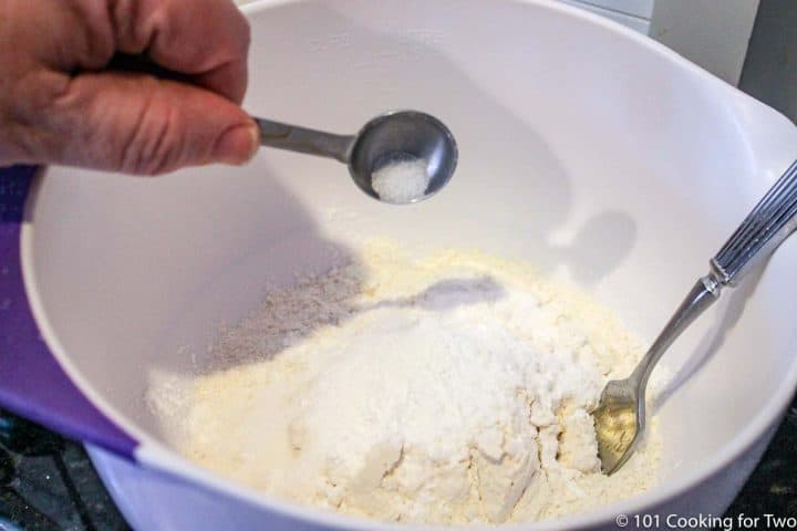 adding all the dry ingredients to a white bowl