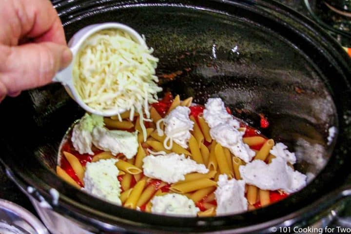 adding cheeses to the first layer of pasta.