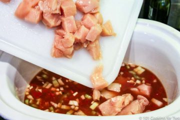 adding cubes of raw chicken to a crock pot