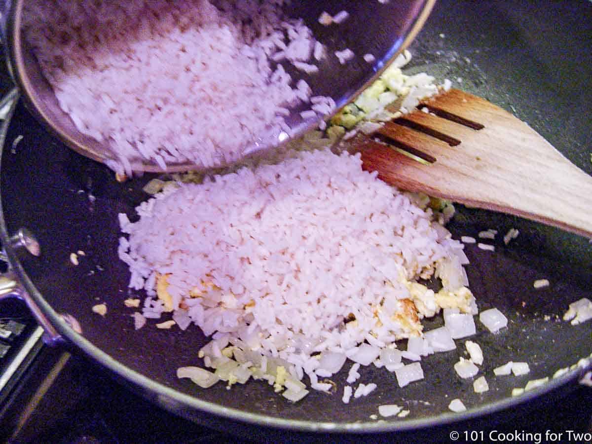adding the rice back into the pan with the egg and onion