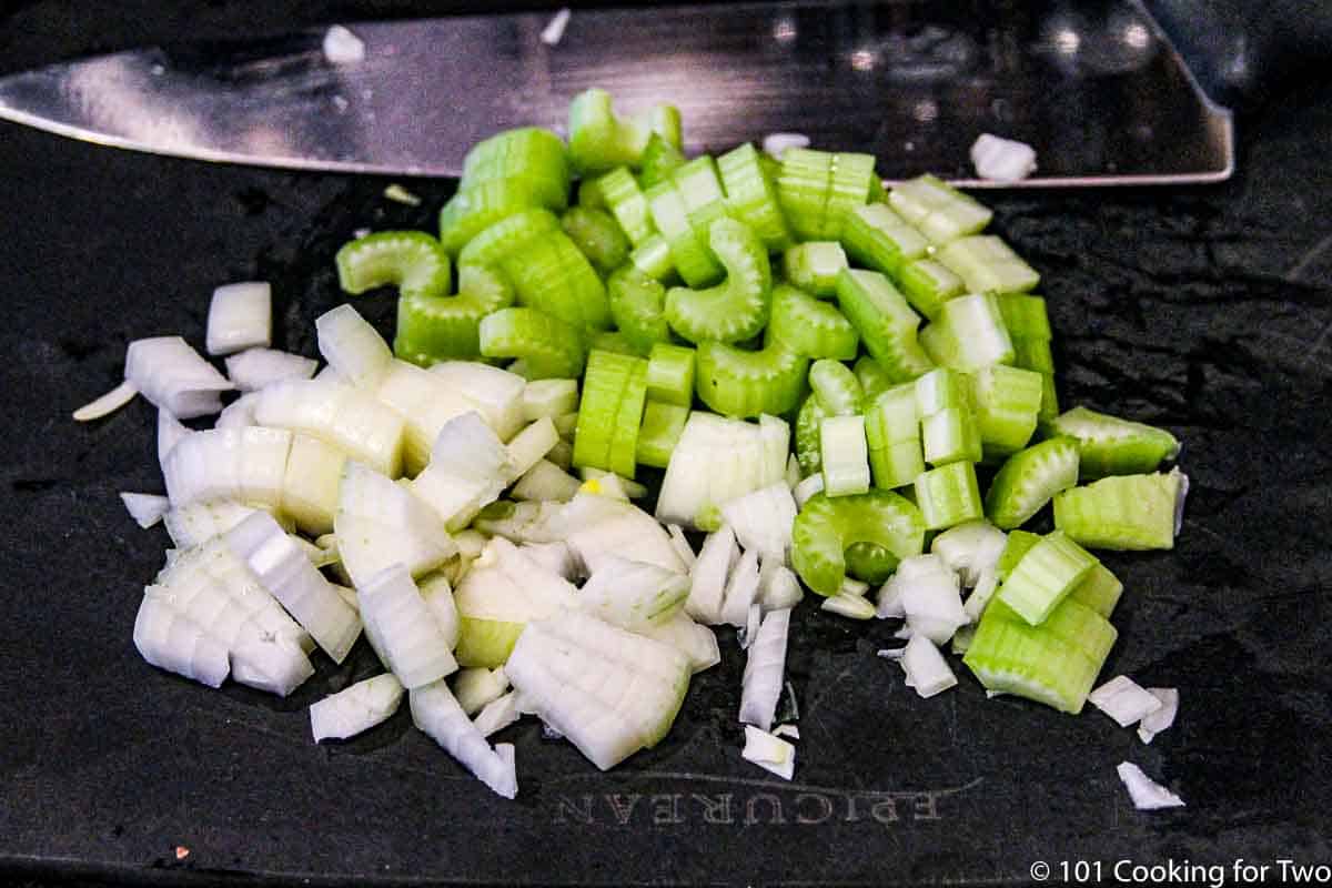 chopped celery and onion on a black board.