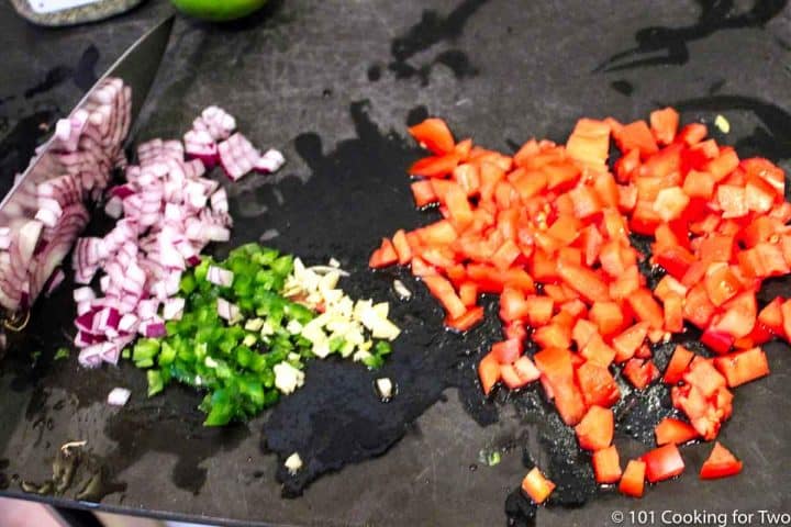 chopped onion with tomato and jalapeno on a black board