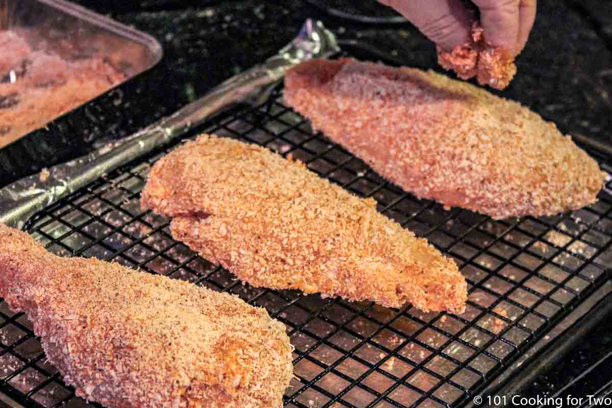 coated chicken breasts on the rack while adding more coating.