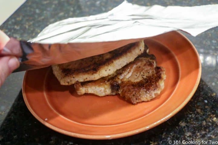 cooked pork chips being tented to keep warm