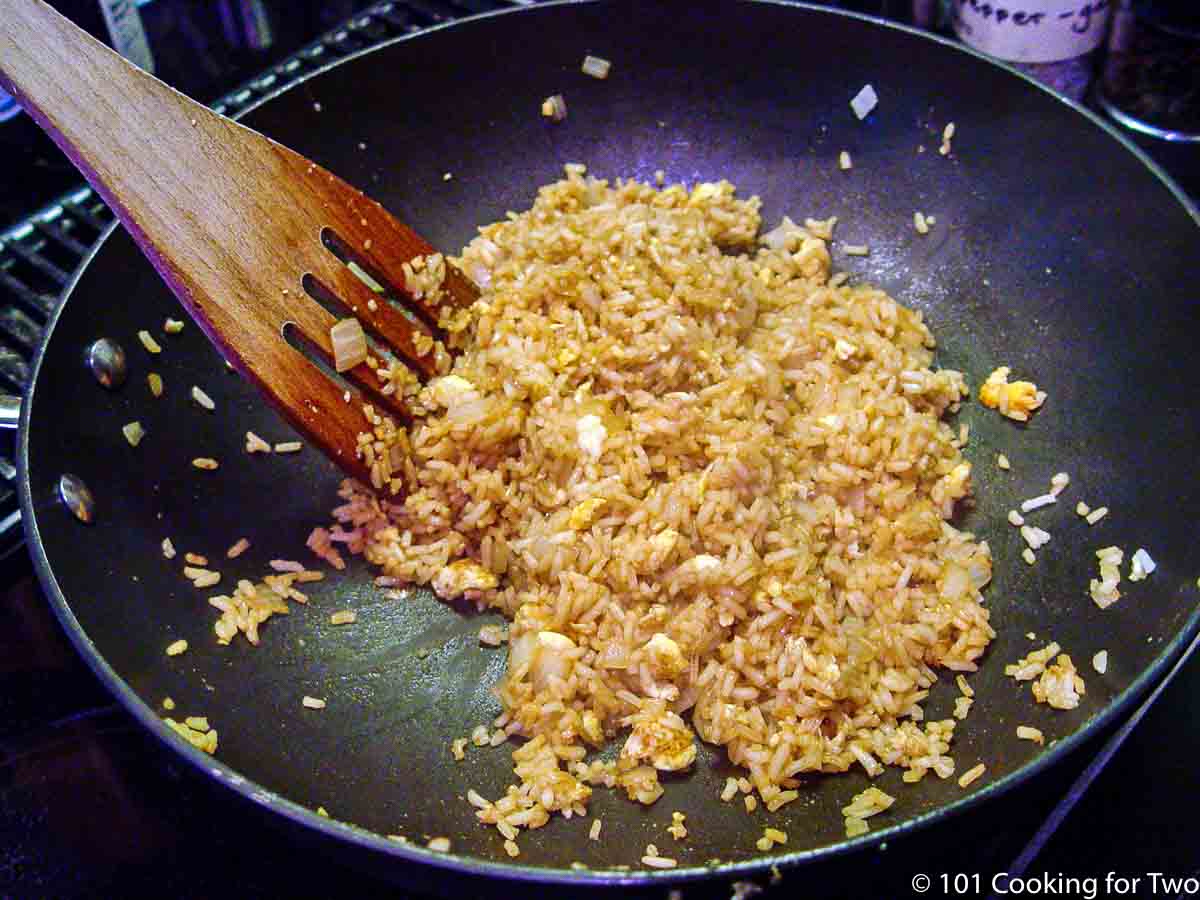 cooking the rice with the other ingredients in a pan.