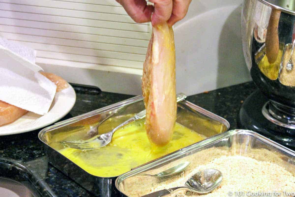 dipping chicken breast in the egg coating.