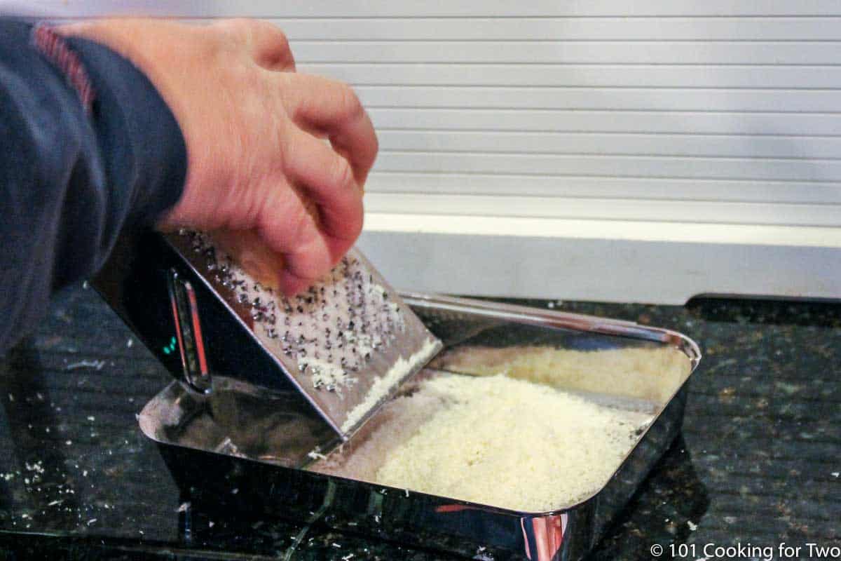 grating Parmesan into a pan.