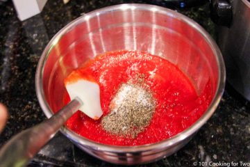 mixing crushed tomatoes with spices in a bowl