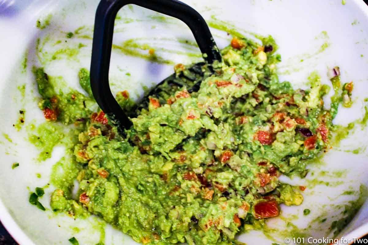 mixing the guacamole together in a bowl.