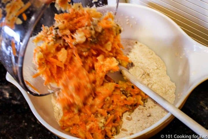 mixing wet ingredient with carrots into dry ingredients