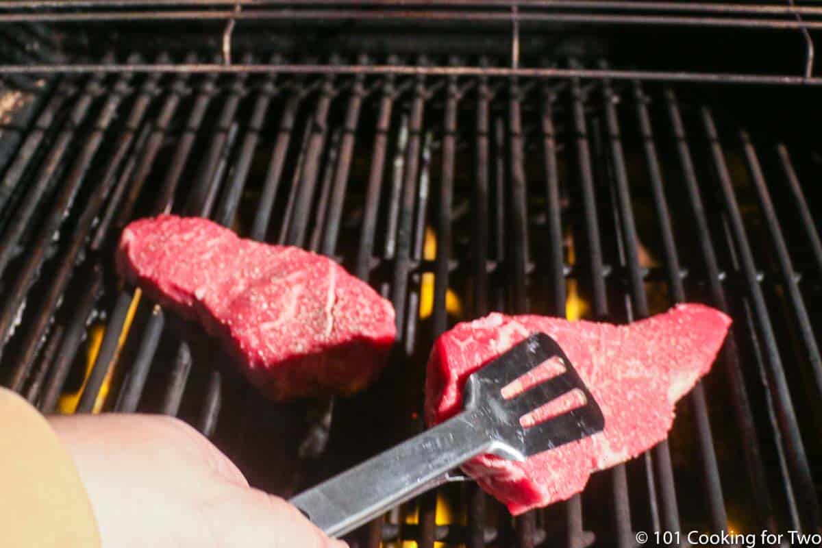 placing strip steaks on the grill