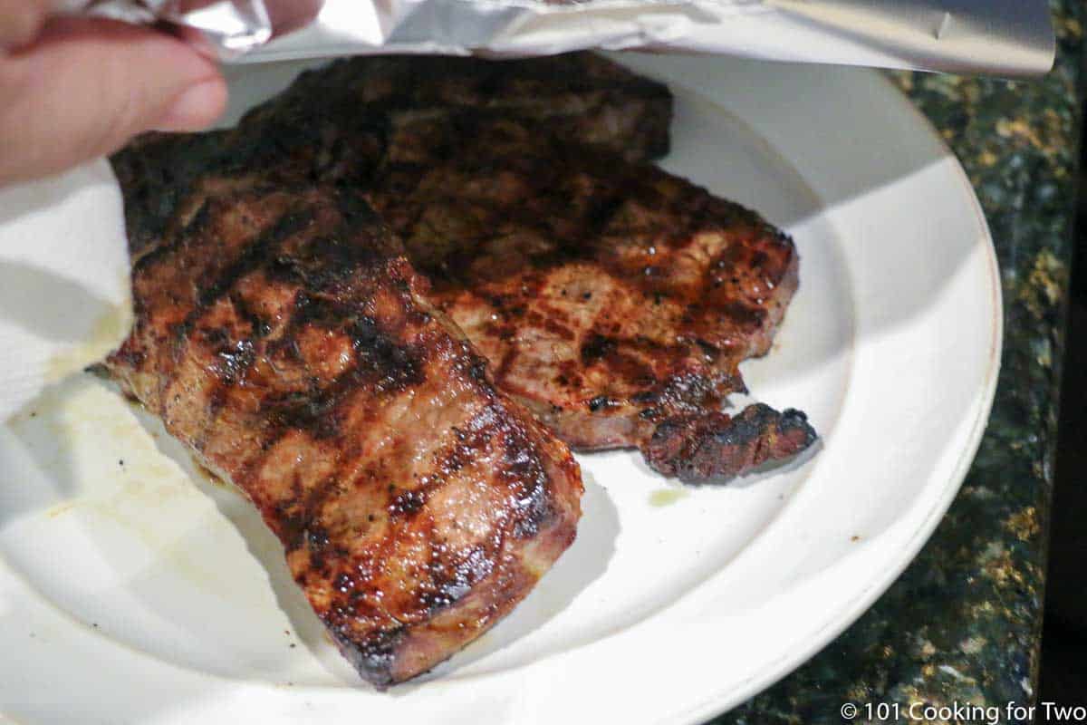 ribeye steaks cooked on a plate being tented