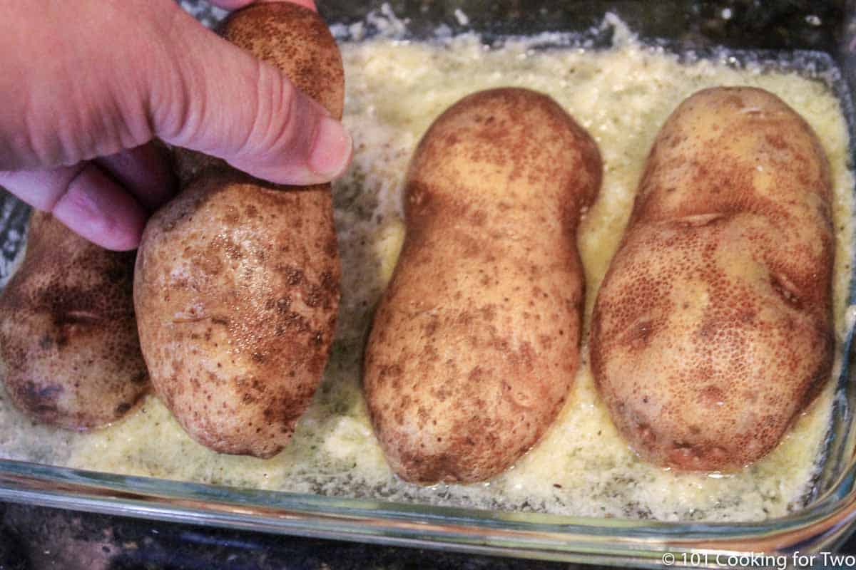 setting cut halves of raw potato on the prepared pan.
