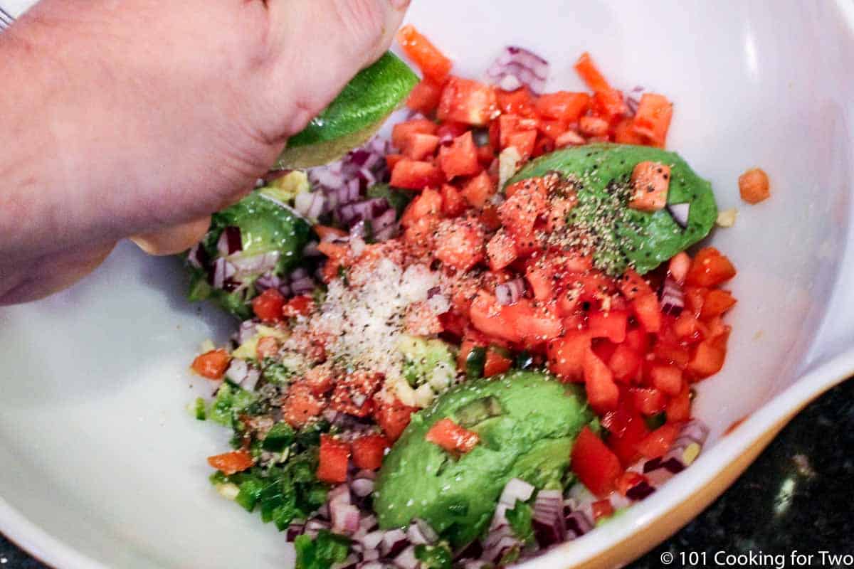 squezing a lime onto other ingredients in a bowl.