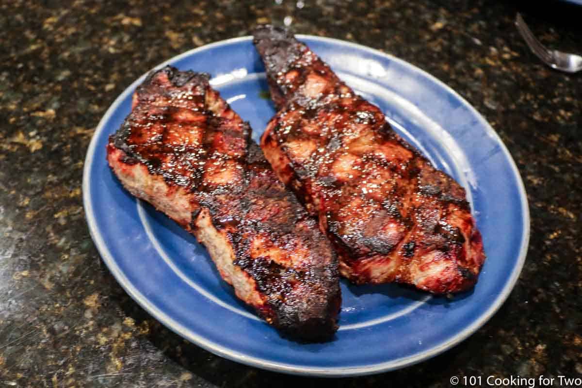 two grilled strip steaks on a blue plate
