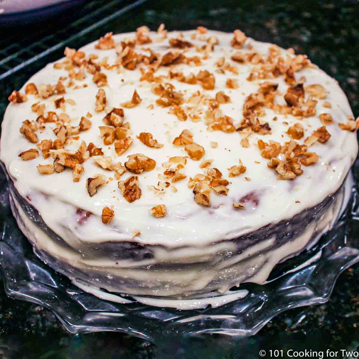 whole carrot cake with frosting and topped with nuts